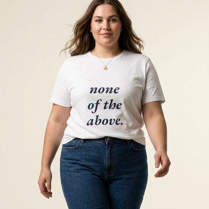 A woman modeling "not a shape" white graphic t-shirt with the text 'none of the above.' printed in dark navy and pink, paired with dark blue jeans against a solid light beige background.