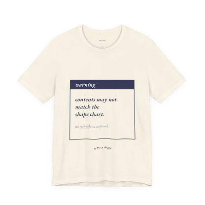 An off-white short-sleeve t-shirt with a graphic print on the front. The print features a dark navy blue box labeled 'warning' with the text 'contents may not match the shape chart.